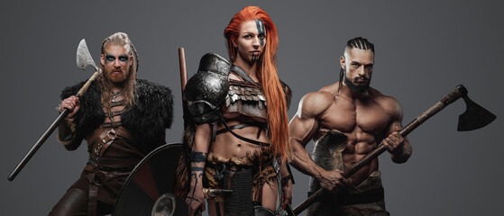 Shot of scandinavian amazon and two warriors dressed in armor armed with axes.