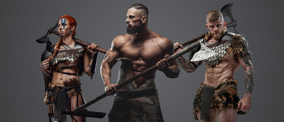 Studio shot of three scandinavian barbarians from past against grey background.