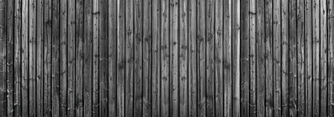 Dunkelgraue Holzwand aus vertikalen Brettern mit intensiver Holzmaserung in Panorama Nahaufnahme