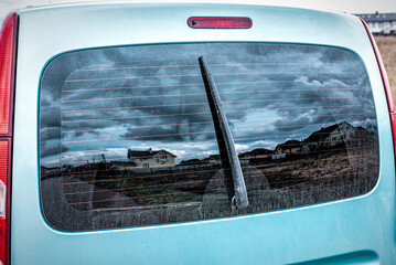 Detail of a rear window of a vehicle dirty by rain with mud