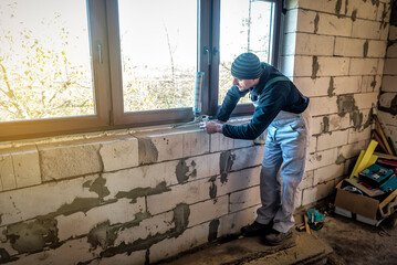 Handyman using polyurethane foam for installing a plastic window