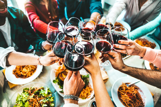 Happy friends toasting red wine glasses at diner party - Group of people having lunch break at bar restaurant - Life style concept with guys and girls hanging out together - Food and beverage