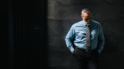 Portrait senior man stressed sad and tired from over working standing on dark wall background. Overworked and worried. CEO business company