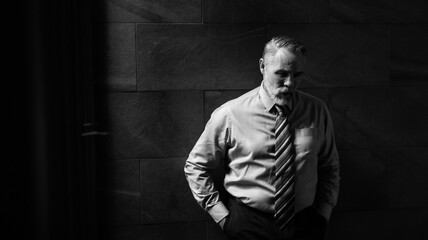 Fototapeta premium Portrait senior man stressed sad and tired from over working standing on dark wall background. Overworked and worried. CEO business company