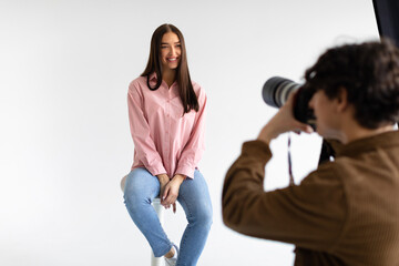 Creating captivating portraits. Photographer taking photos of young european lady, having photoshoot on white background