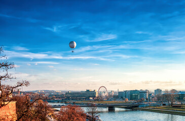 Krakow city over Vistula river with flying hot air balloon and Ferris wheel, Poland