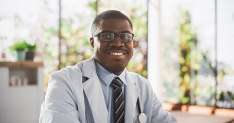 Portrait of a Black Medical Health Care Professional Posing for Camera, Smiling and Looking at Camera. African Clinic Physician Wearing Glasses and a White Coat Working in Hospital Office