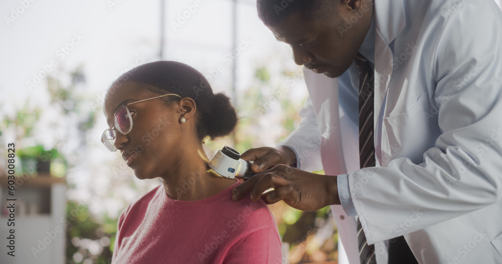 Wall mural african skin care professional using a dermatoscope to examine neck tissue on the skin of an attract