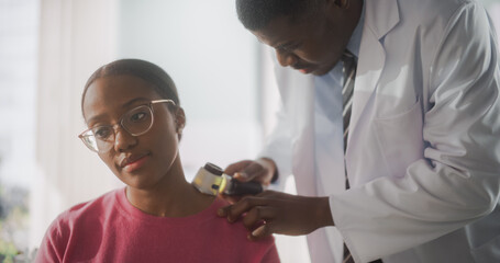 African American Dermatologist Using a Dermatoscope to Identify Worrying Cancerogenic Tissues on...