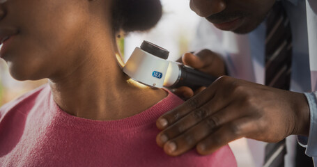 Close Up of a Black Dermatologist Using a Medical Magnifying Glass to Inspect any Damages on the Skin of a Female African Patient During a Health Check Visit to a Clinic. Doctor Working in Hospital