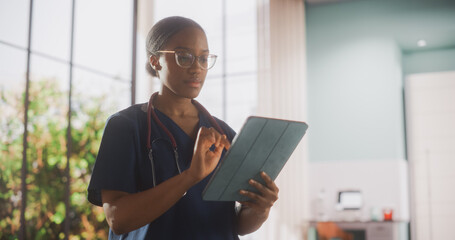 African Healthcare Nurse Using Tablet Computer for Day-to-Day Hospital Operations. Beautiful Young Clinic Professional Doing Online Medical Work in Modern Office in Public Health Care Facility