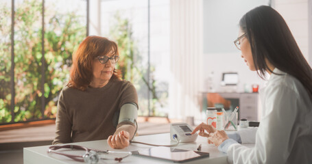 Female Physician Using Sphygmomanometer to Measure Blood Pressure During a Consultation with a Senior Woman in Health Clinic. Nurse Diagnosing Elderly Patient