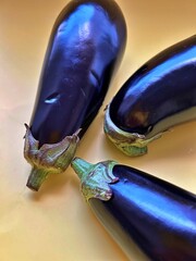 Naklejka na ściany i meble dark, purple eggplants, placed on a purple background, dark and long eggplants, fresh vegetables, natural products from the garden, harvest from the plot, cut eggplant