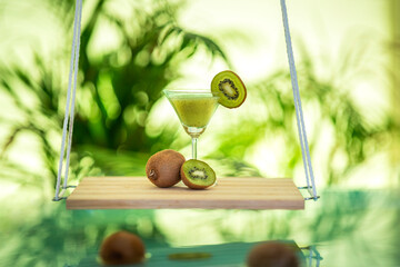 Fototapeta premium Beautiful kiwi juice with sliced kiwi fruits background, wooden hanging swing with juice glass