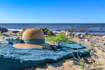 Straw hat and flip-flops on a blue towel on a natural beach, summer holidays near the tourist resort Boltenhagen, Baltic Sea, Germany, copy space, view from above, selected focus