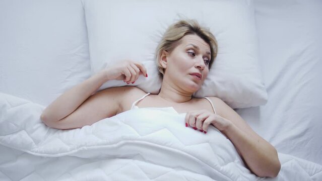 Irritated restless woman trying to wake up in morning, bad mood because of bad sleeping conditions, sleep deprivation due to uncomfortable posture and sleep apnea