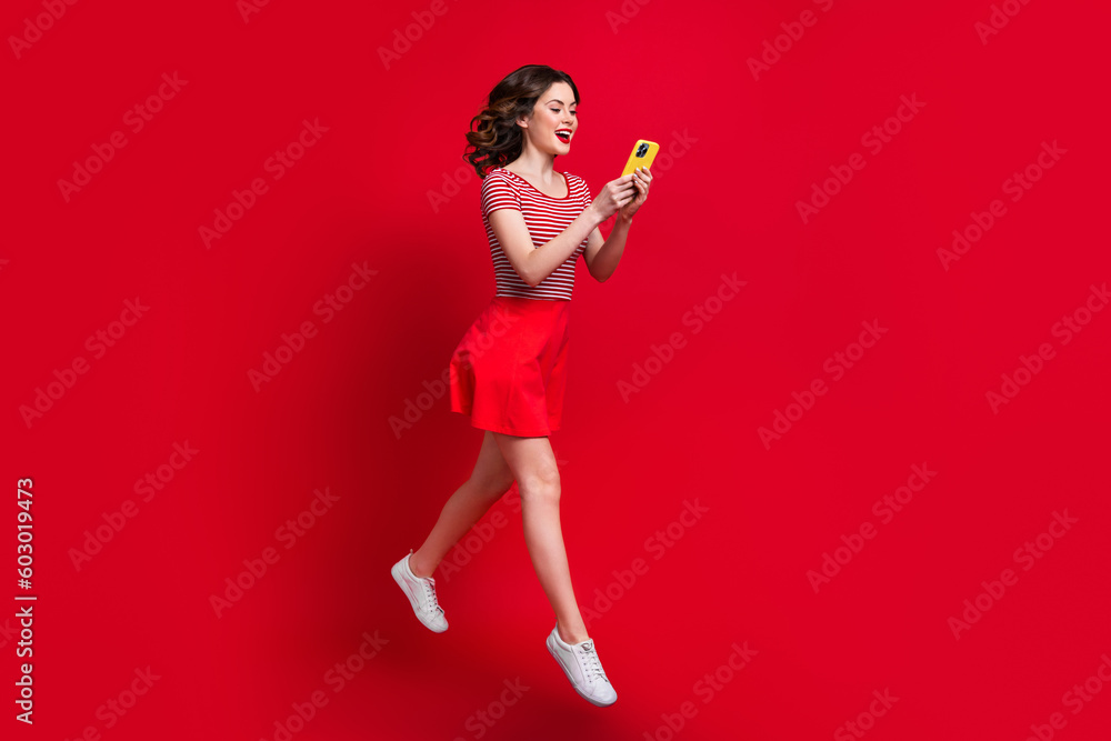 Poster Full length photo of positive lady wear stylish clothes use modern device hurry shop sale walk empty space isolated red color background