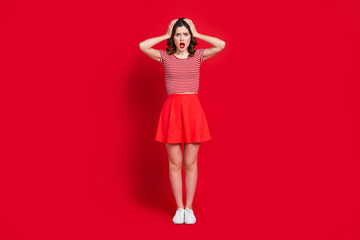 Full size photo of shocked girl arms touch head open mouth staring cant believe isolated on red color background