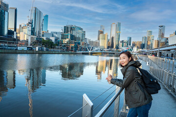 Fototapeta na wymiar Asian women traveling along the Yara river side streets with urban high rise buildings, lively city views and central business districts in Melbourne, Victoria, Australia 