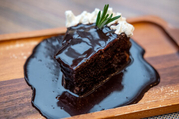Tasty chocolate cake with whipped cream served on wooden plate