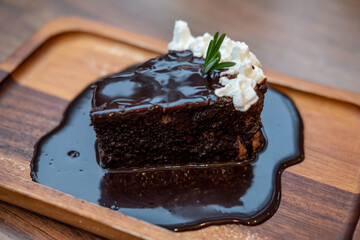 Tasty chocolate cake with whipped cream served on wooden plate