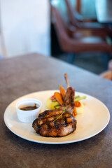 Grilled pork chop served on plate with sauce