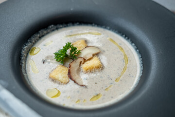 Mushroom soup served in black bowl in the restaurant