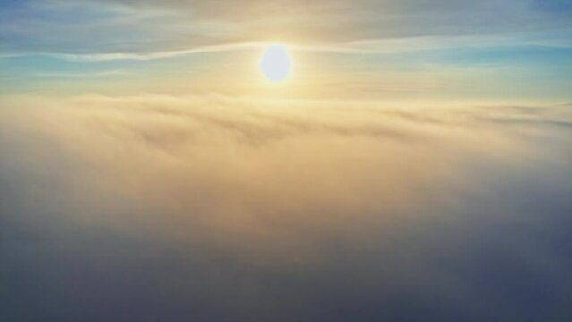 Aerial view from a drone flying above the lush clouds, bright Sun