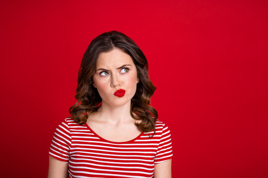 Photo of pretty moody girl look empty space have grin face not sure good bad news pout red lips isolated red maroon color background
