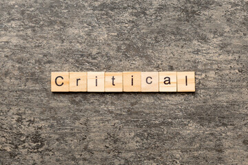 critical word written on wood block. critical text on table, concept
