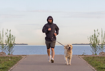 A man on a morning run with his golden retriever. Sports in the early morning. 