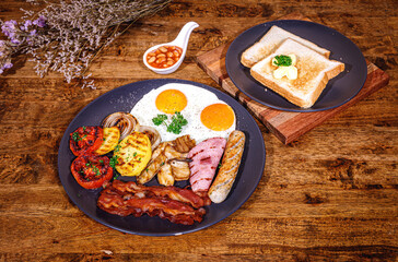 English Breakfast in cooking pan with fried eggs, sausages, bacon, beans, toasts on dark stone background copy space