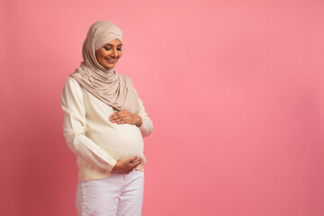 Beautiful pregnant muslim lady in hijab embracing her big belly