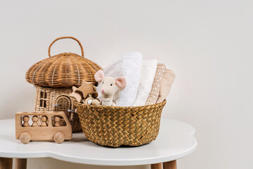 Stack of baby clothes with cute little toy mouse in the basket and accessories for newborn. Cotton...