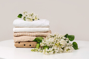Stack of baby clothes with flowers. Cotton clothes and muslin swaddle blanket in pastel colors. Clean freshly laundered, neatly folded kids clothes. - obrazy, fototapety, plakaty