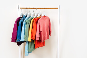 Clothing Rack with children's outfits close up. Fashion clothes in  rainbow colors on hangers in wardrobe. Kids wardrobe. Set of kids clothes and accessories.