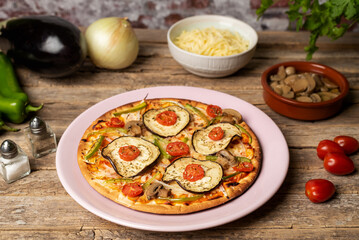 Vegetable pizza for vegetarians ready to eat, with eggplant, pepper, cherry tomato, onion and mushroom, close-up.