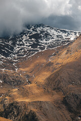 Vertical shot of the high snowy mountain ranges of the Pyrenees on an autumn day reaching up to a cloudy sky. Travel concept for climbing and trekking lovers. Copyspace