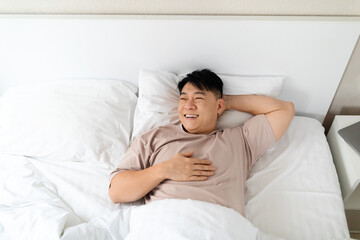 Top view of asian man lying in bed at home