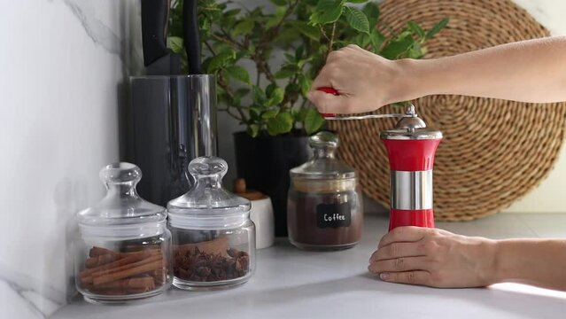 Female hands grind coffee beans in a grinder on the background of a modern kitchen. Grinding your own coffee.