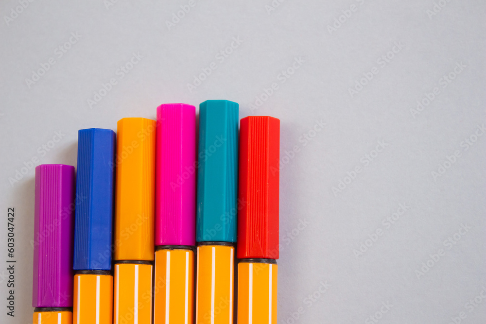 Poster top view of colorful markers on a grey background with copy space.