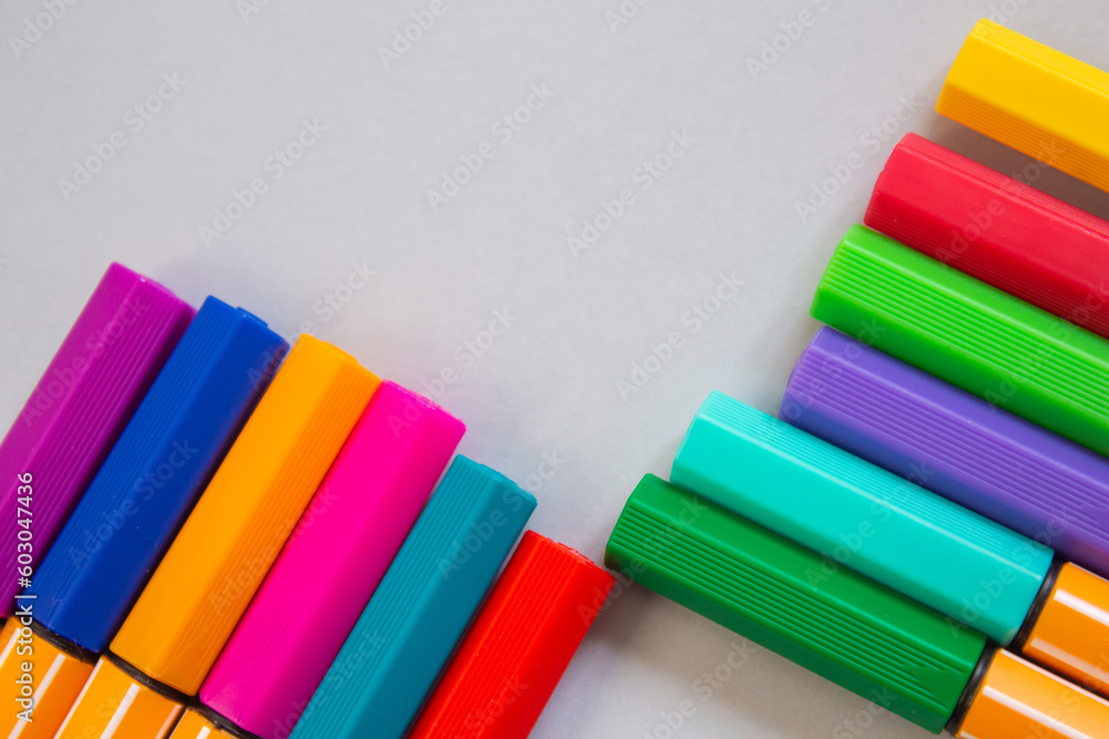 Poster top view of colorful markers on a grey background with copy space.