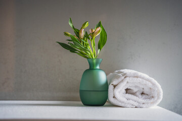Minimalism style interior decor. Fresh flowers in green glass vase on the natural stone shelf