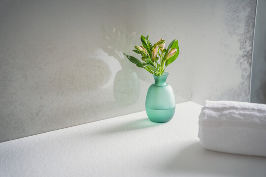 Minimalism style interior decor. Fresh flowers in green glass vase on the natural stone shelf
