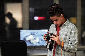Young photographer concentrating on his work, he photographing on digital camera in studio