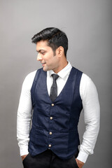 Studio shot of cheerful, young, handsome Indian business man in formal wear against grey background. Male model. Fashion Portrait.