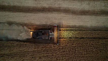 Fototapeta na wymiar Aerial shot at night harvester gathering crops from agricultural fields. Global food crisis and grain supply chains