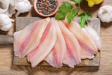 fresh fish fillet of tilapia with ingredients for cooking, top view