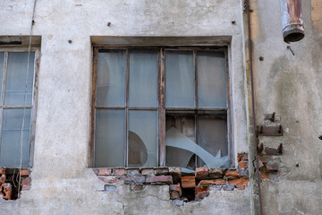 Broken industrial window in a concrete wall with falling bricks