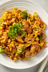 Stir-fried egg noodles with chicken breast in a white plate top view